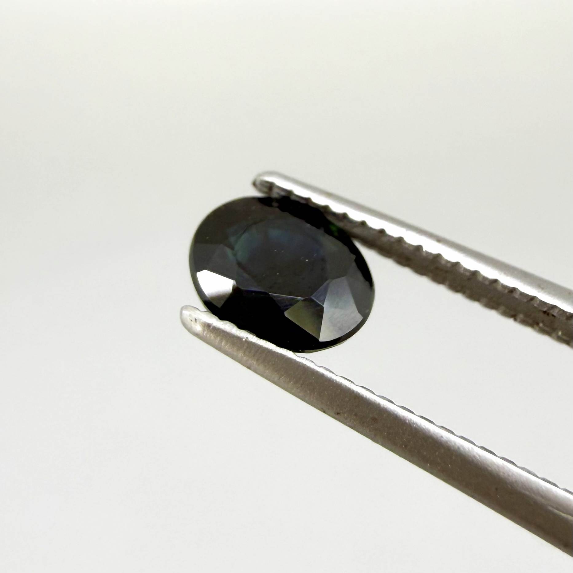 Oval dark blue heated sapphire from Laos weighing 0.87 ct, featuring a deep blue color and eye-clean clarity.