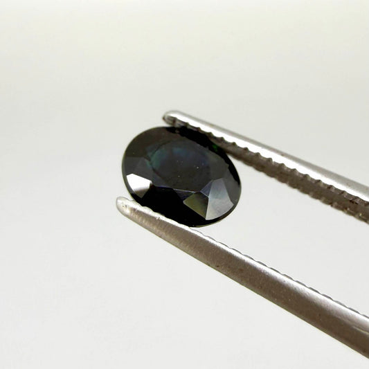 Oval dark blue heated sapphire from Laos weighing 0.87 ct, featuring a deep blue color and eye-clean clarity.
