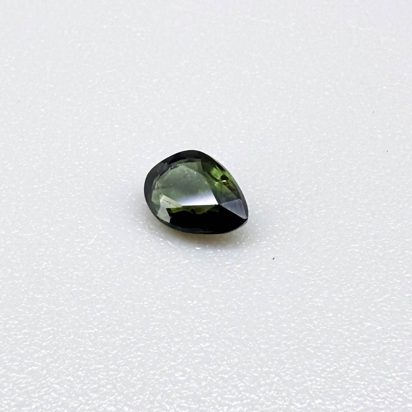 Olive green pear-shaped Laos sapphire weighing 0.39 ct, heated and eye-clean.