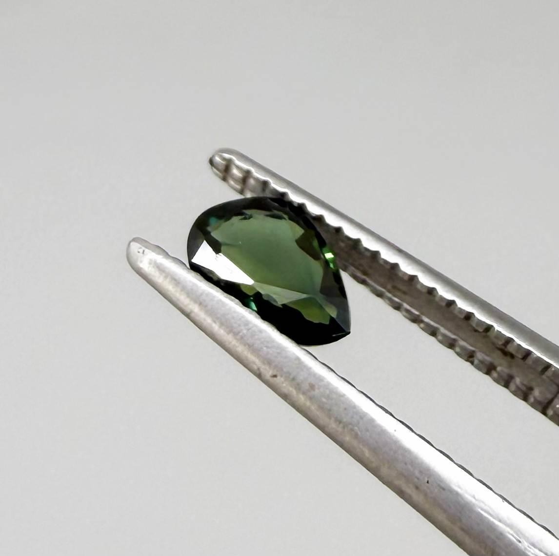 Olive green pear-shaped Laos sapphire weighing 0.39 ct, heated and eye-clean.