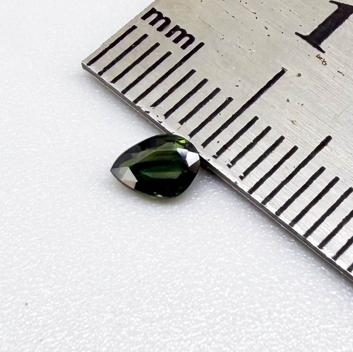 Olive green pear-shaped Laos sapphire weighing 0.39 ct, heated and eye-clean.