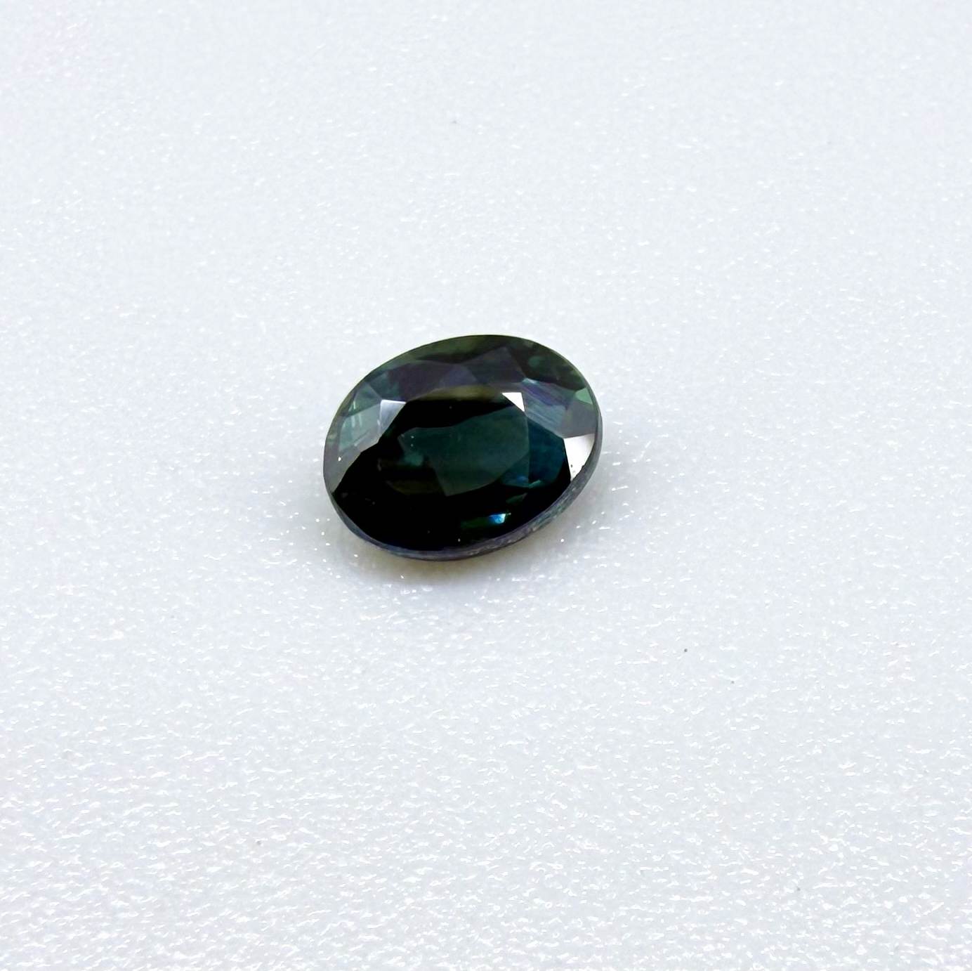 0.57 ct teal blue Laos sapphire in oval cut, heated and eye-clean with vivid blue-green tones.