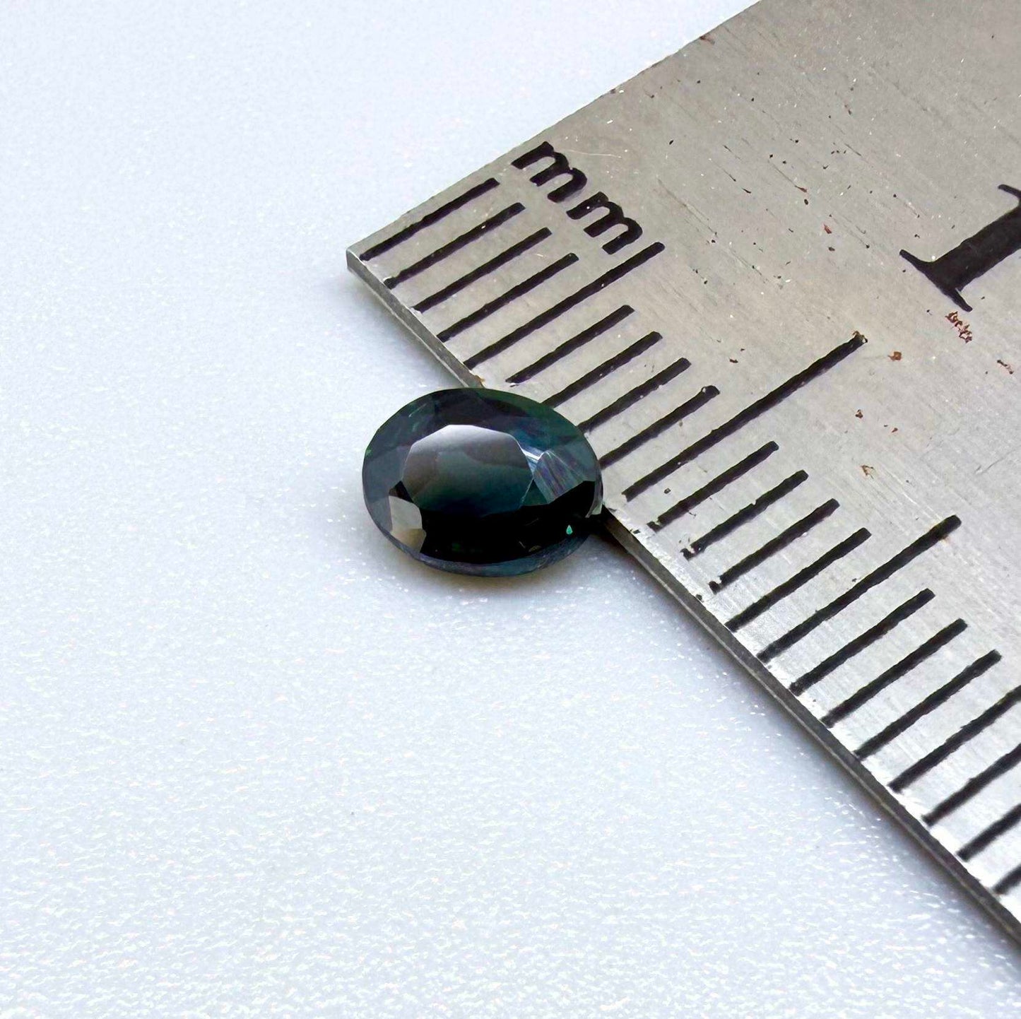 0.57 ct teal blue Laos sapphire in oval cut, heated and eye-clean with vivid blue-green tones.
