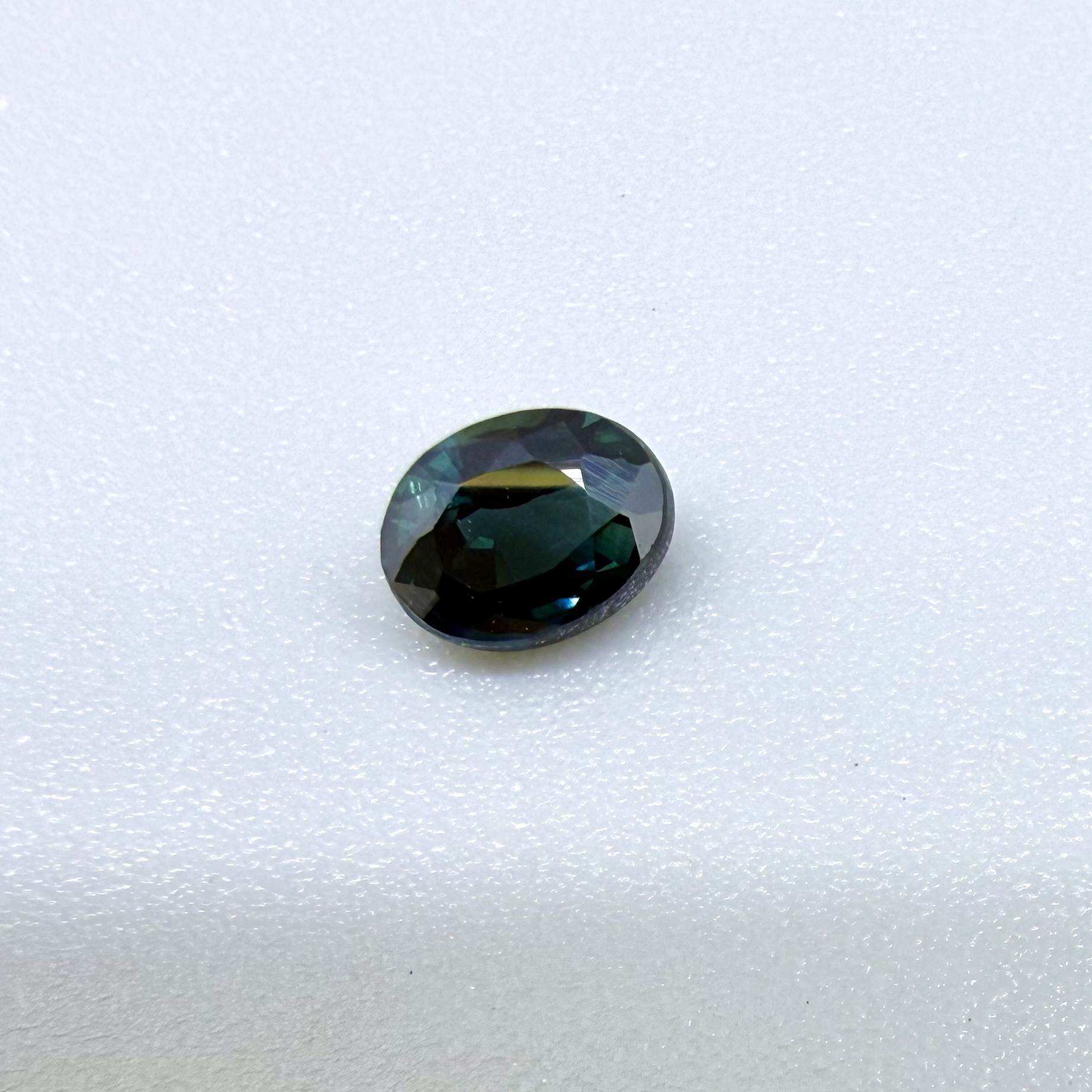 0.57 ct teal blue Laos sapphire in oval cut, heated and eye-clean with vivid blue-green tones.