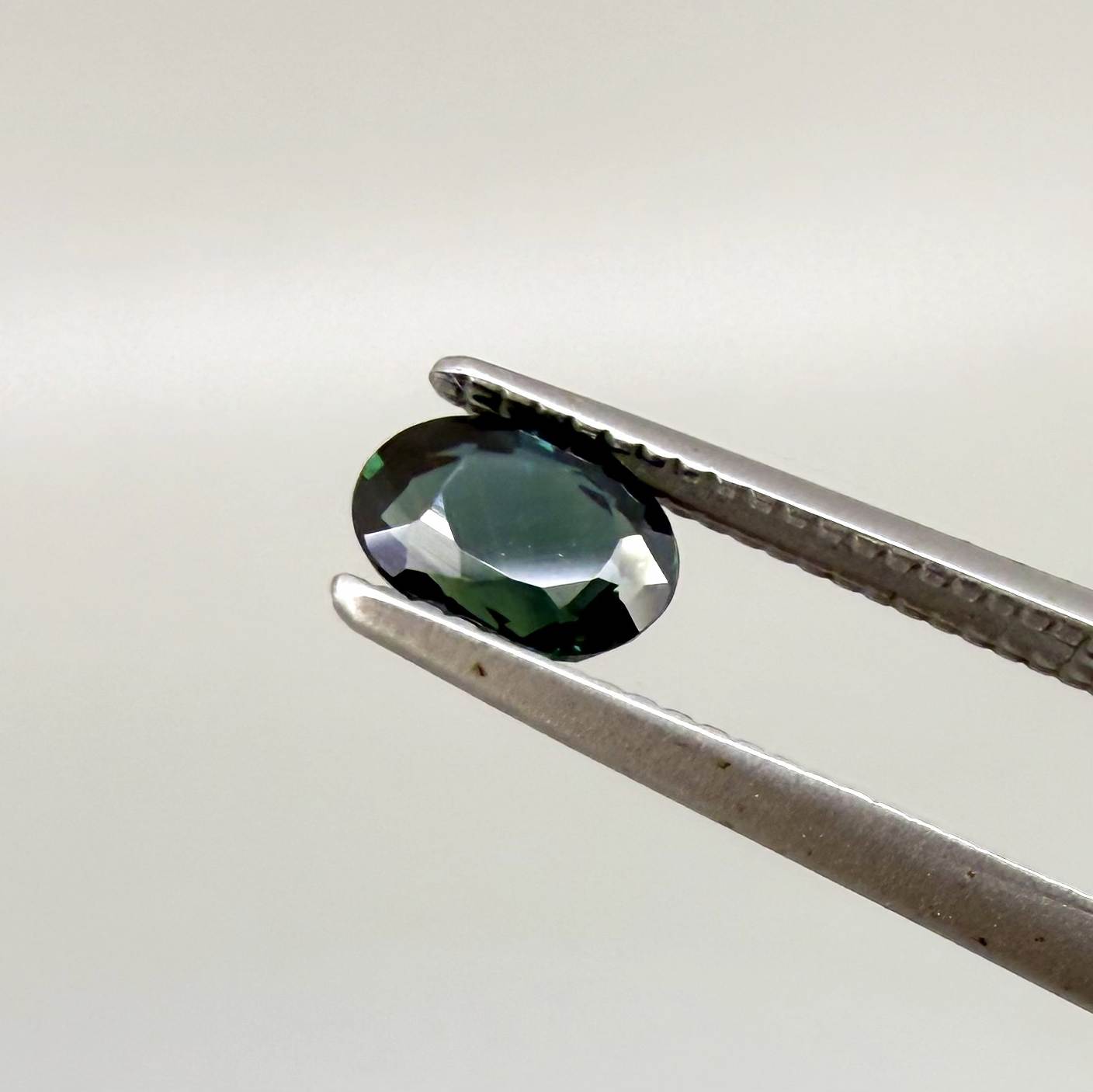 0.57 ct teal blue Laos sapphire in oval cut, heated and eye-clean with vivid blue-green tones.