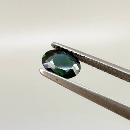 0.57 ct teal blue Laos sapphire in oval cut, heated and eye-clean with vivid blue-green tones.