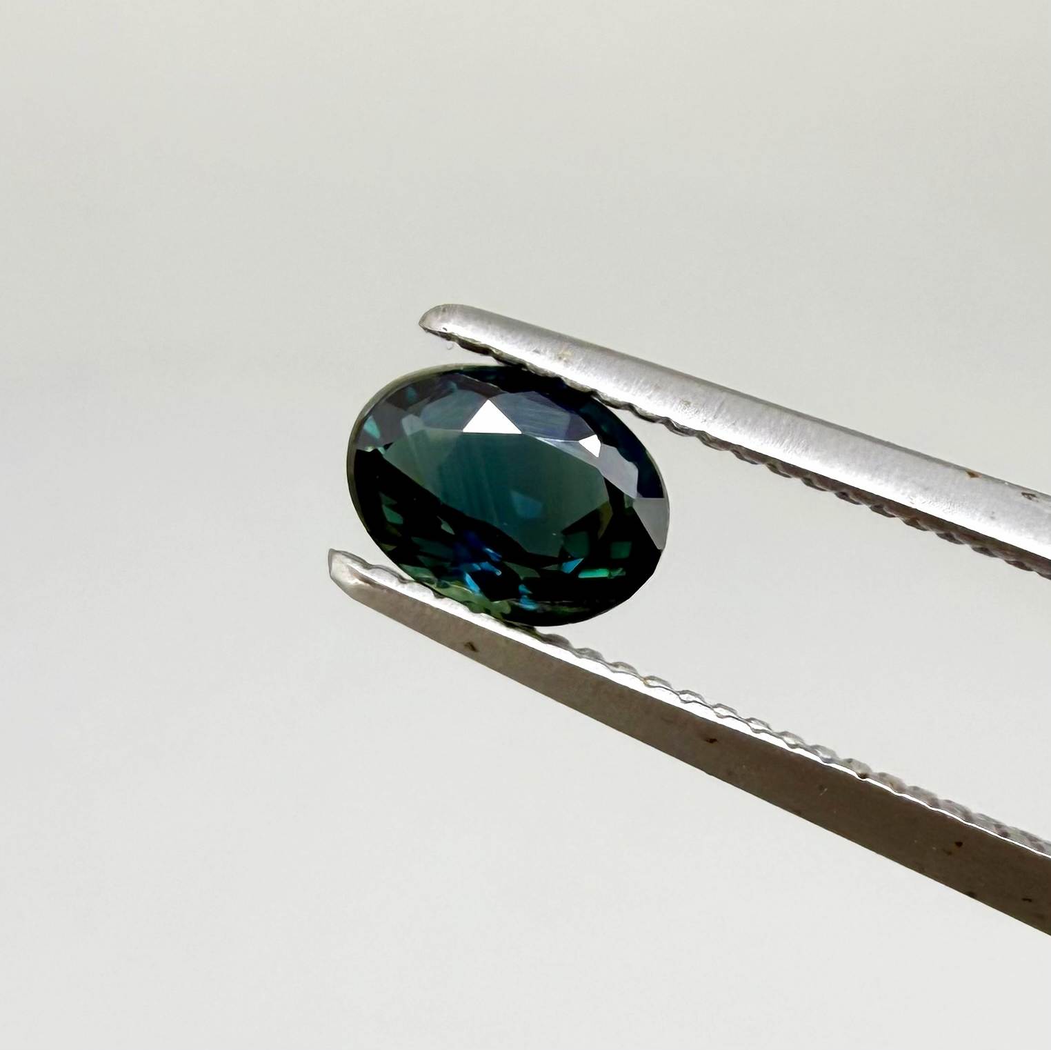 0.57 ct teal blue Laos sapphire in oval cut, heated and eye-clean with vivid blue-green tones.