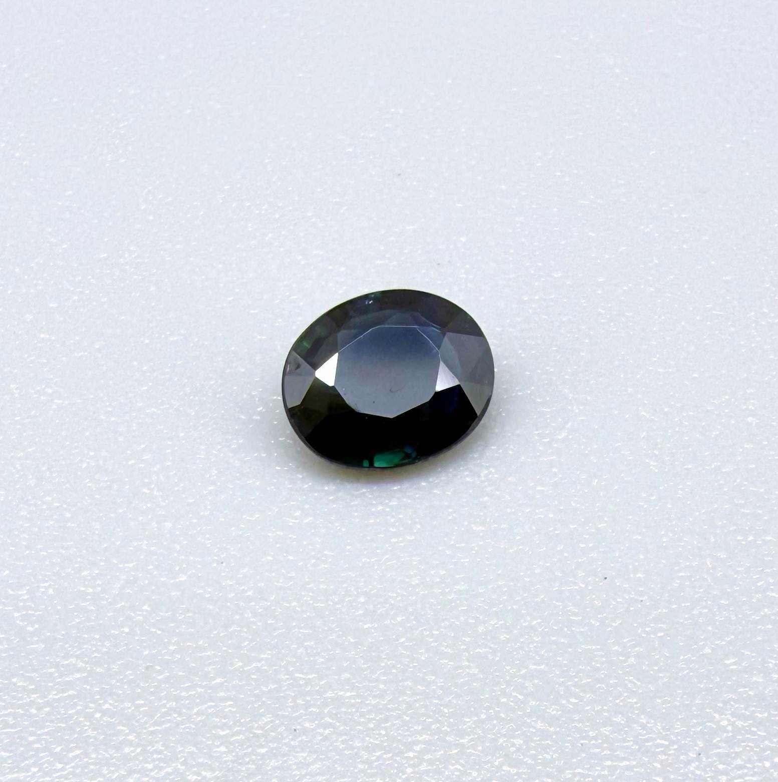 0.55 ct deep teal blue Laos sapphire in oval cut, heated and eye-clean with captivating blue-green tones.