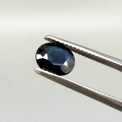 0.55 ct deep teal blue Laos sapphire in oval cut, heated and eye-clean with captivating blue-green tones.
