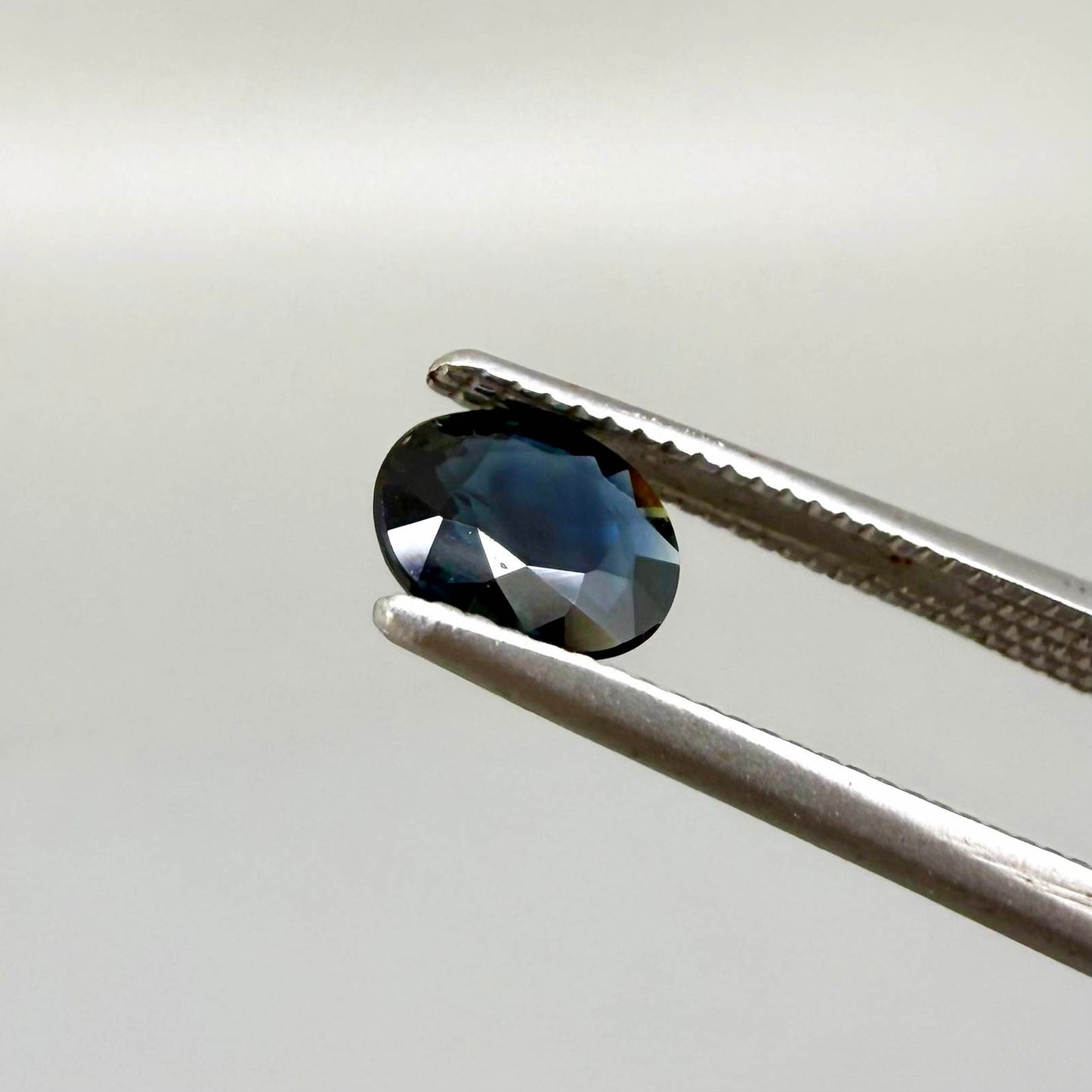 0.55 ct deep teal blue Laos sapphire in oval cut, heated and eye-clean with captivating blue-green tones.