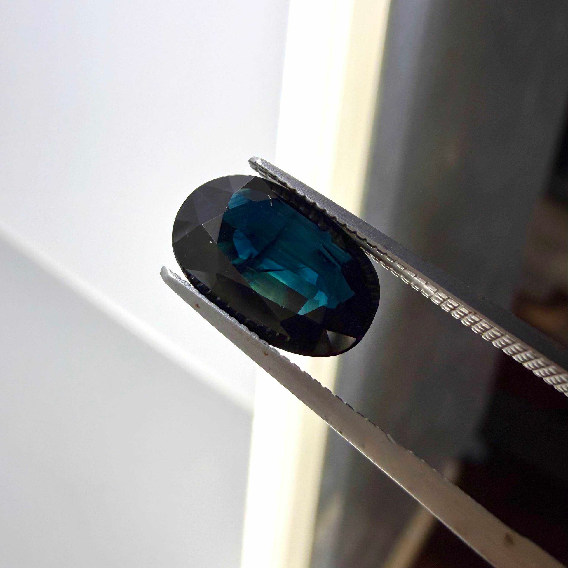 Natural heated deep teal Laos sapphire, 3.18 ct oval with eye-clean clarity and vivid blue-green flashes.