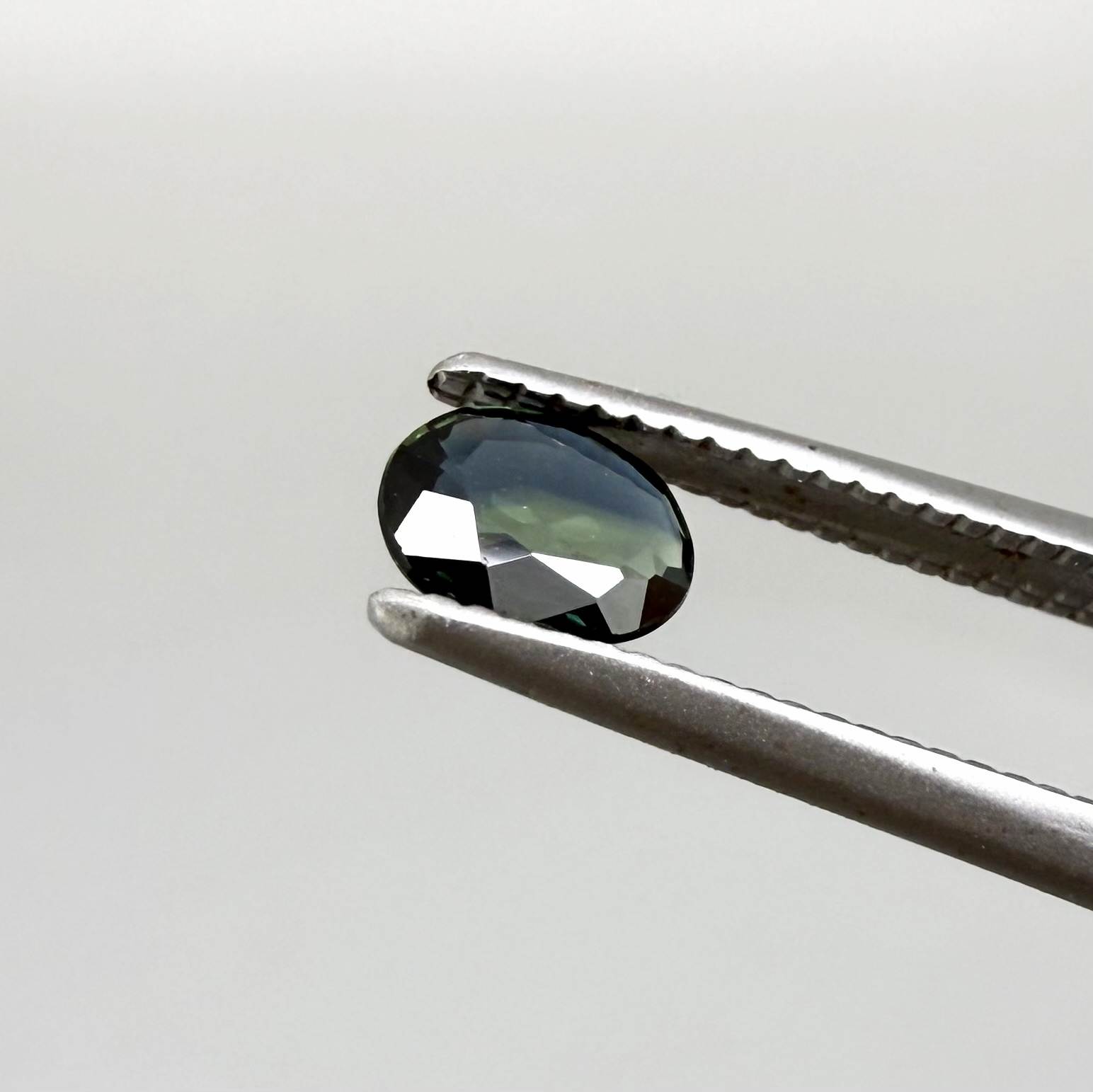 0.28 ct natural parti teal Laos sapphire with oval faceted cut and blue green colour zoning