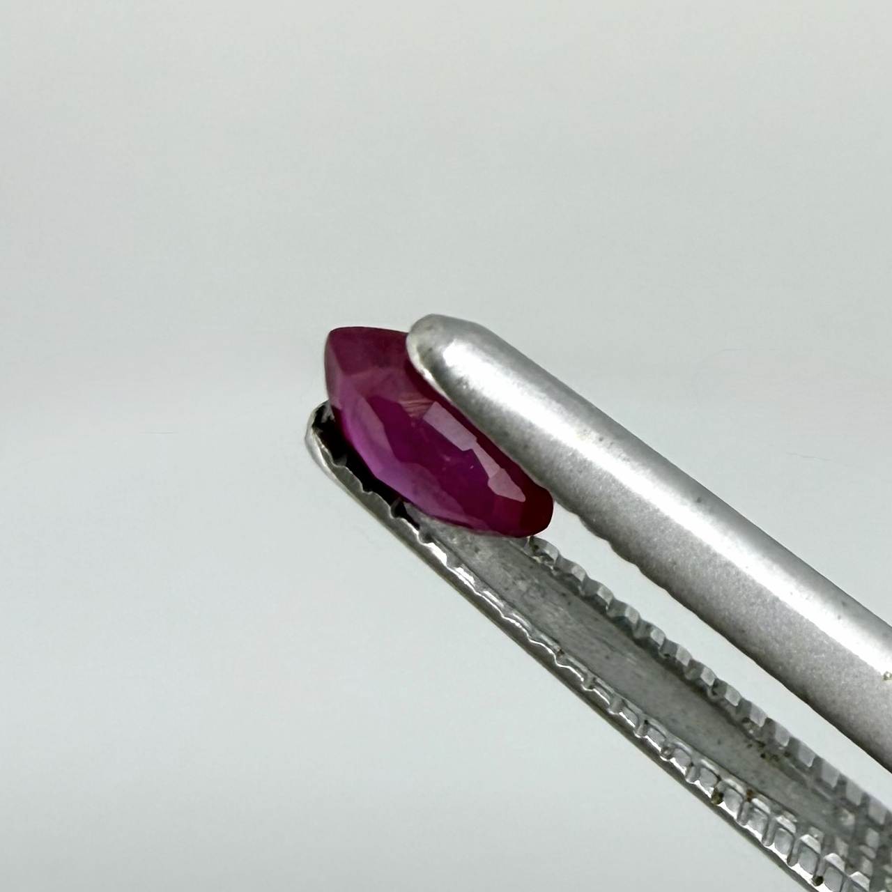 A faceted marquise-cut ruby with deep magenta-red coloration, 0.18 ct of weight with slightly silky appearance and fine natural inclusions