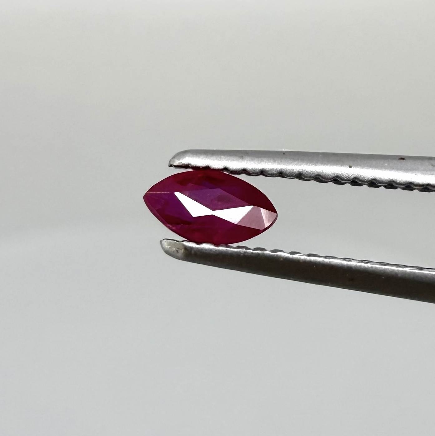 A faceted marquise-cut ruby with deep magenta-red coloration, 0.18 ct of weight with slightly silky appearance and fine natural inclusions