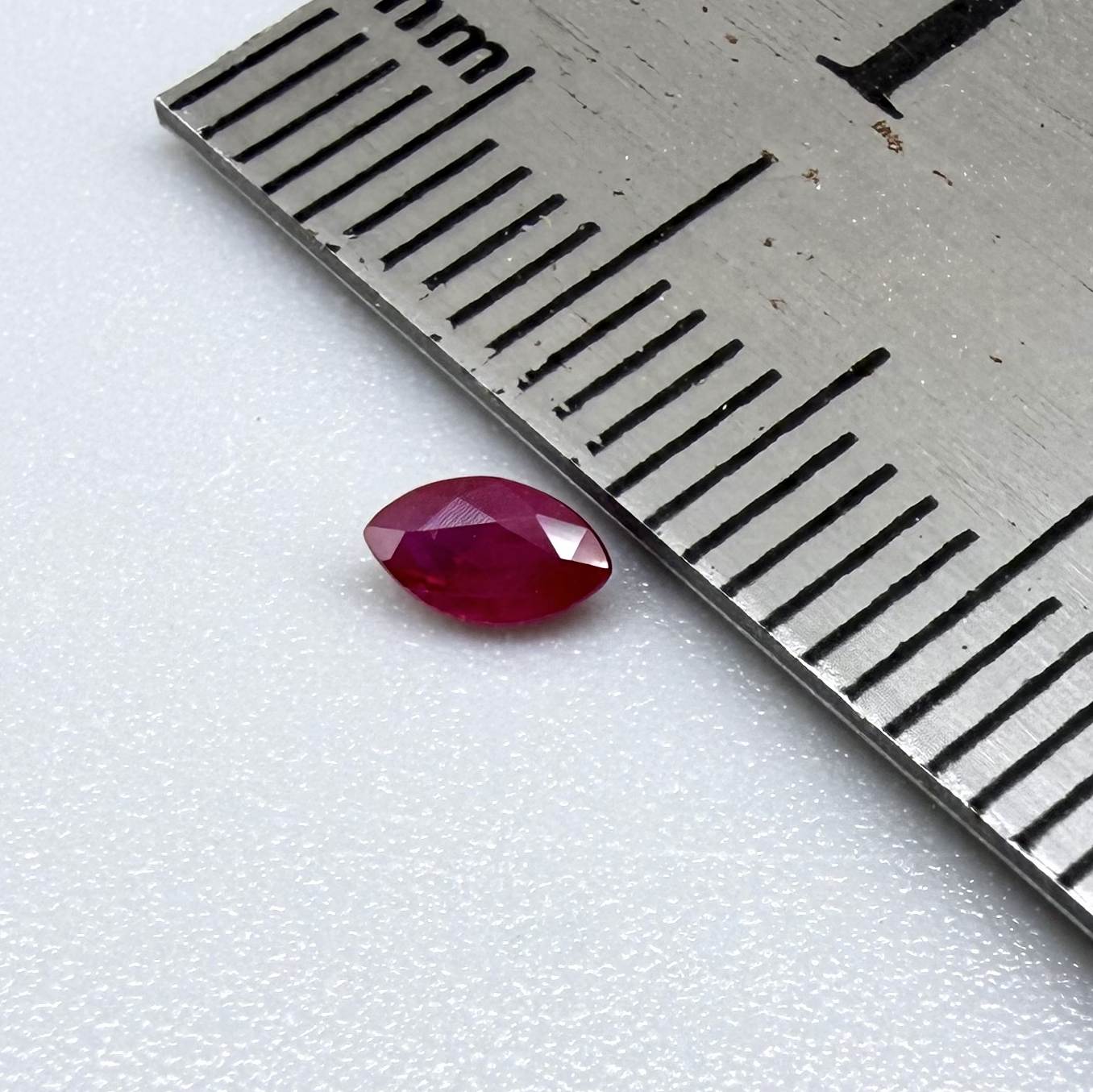 A faceted marquise-cut ruby with deep magenta-red coloration, 0.18 ct of weight with slightly silky appearance and fine natural inclusions