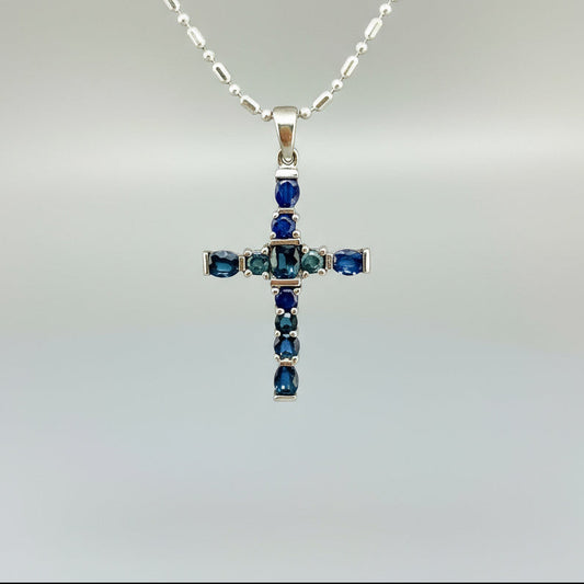 Handcrafted cross pendant with blue sapphires set in white-gold-plated sterling silver.