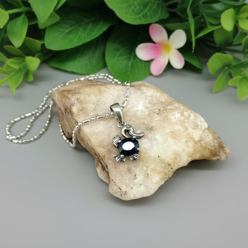 White-gold-plated silver pendant shaped like a duck with a natural sapphire body.