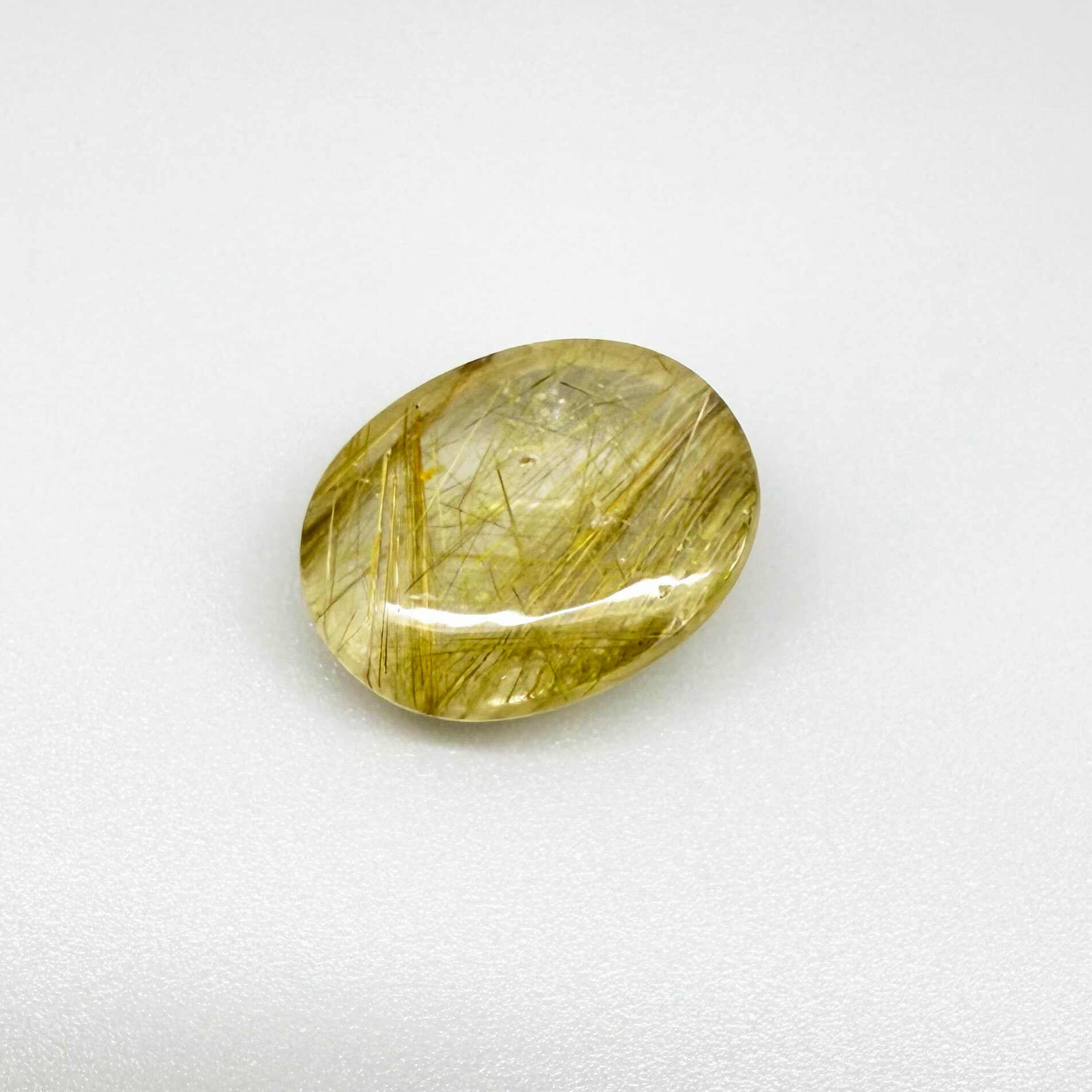 23.3 ct natural Rutilated Quartz with golden rutile inclusions, faceted cut, transparent body and visible needle patterns.