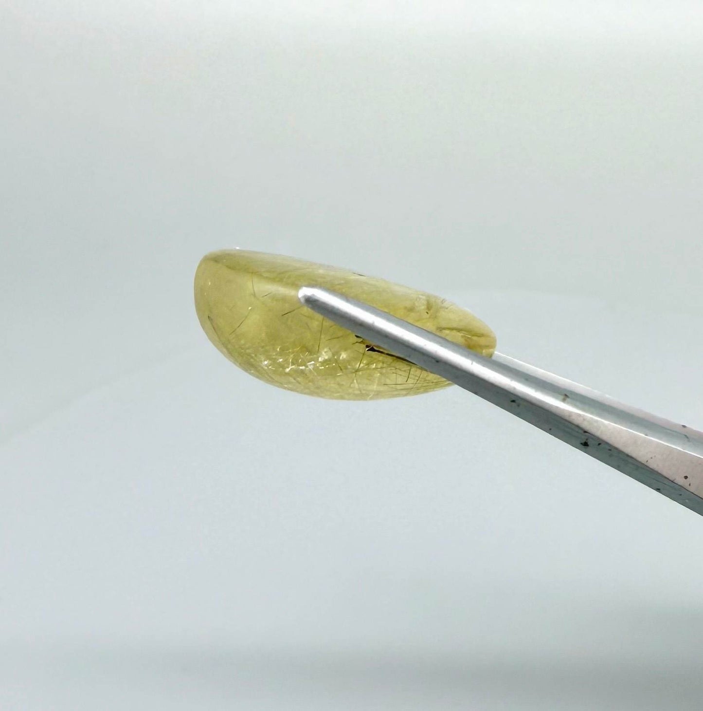 23.3 ct natural Rutilated Quartz with golden rutile inclusions, faceted cut, transparent body and visible needle patterns.