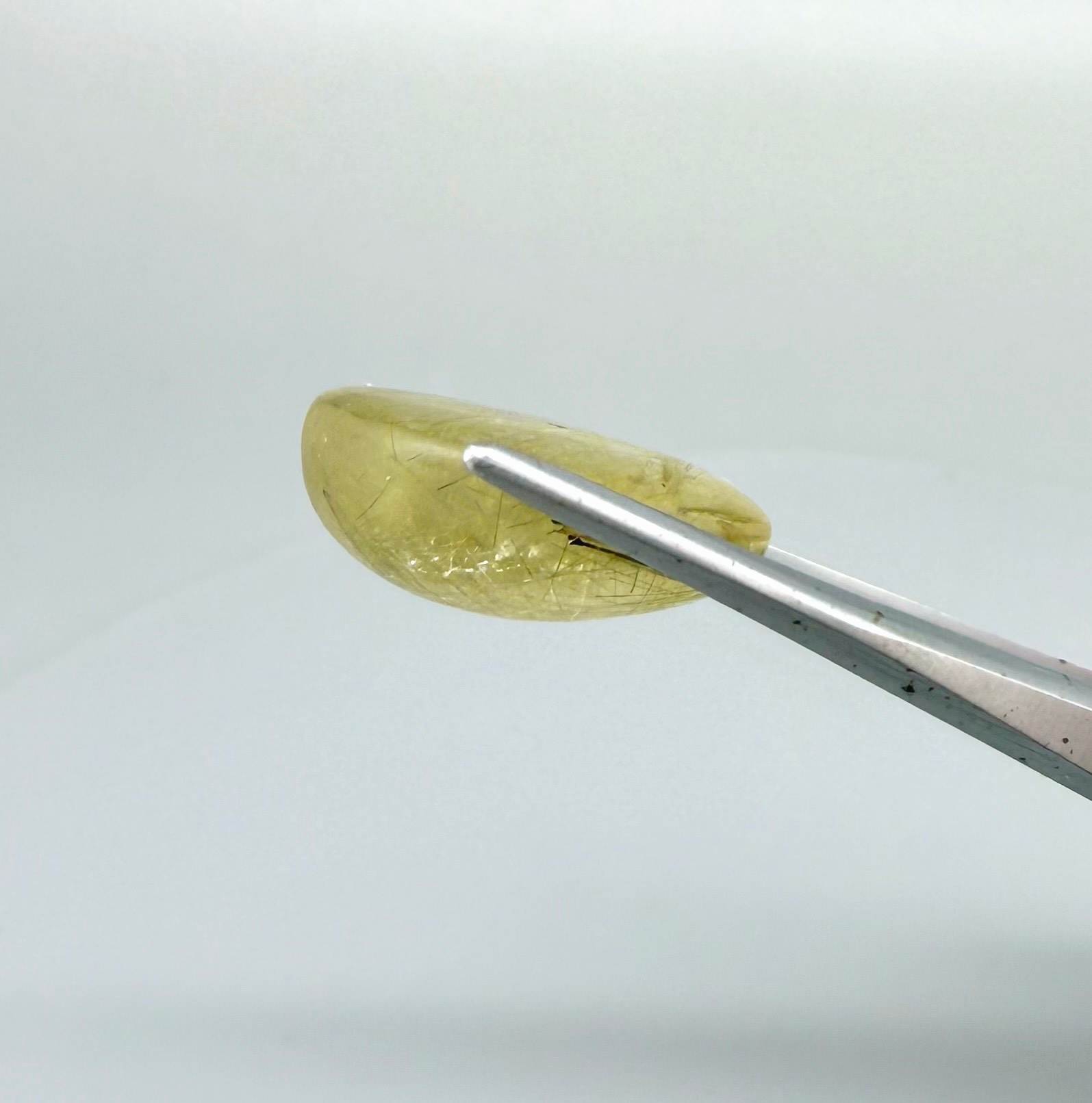 23.3 ct natural Rutilated Quartz with golden rutile inclusions, faceted cut, transparent body and visible needle patterns.