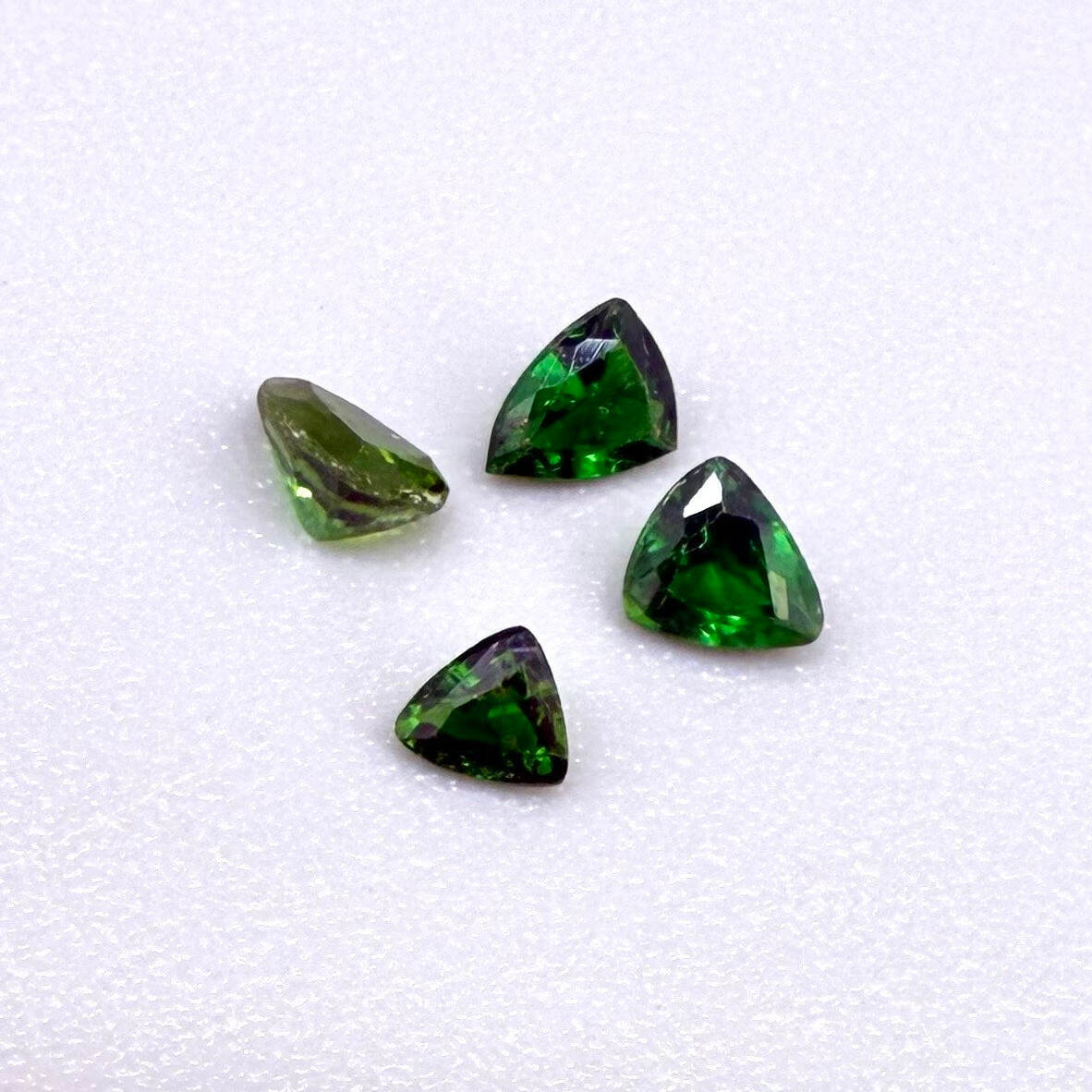 Small lot of four natural vibrant-green diopside stones, trillion cut, total 0.54 ct.