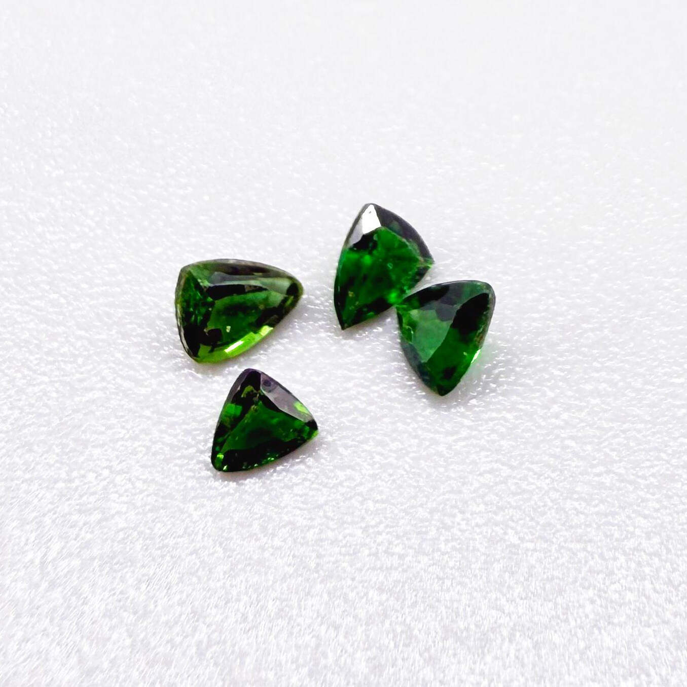 Small lot of four natural vibrant-green diopside stones, trillion cut, total 0.54 ct.