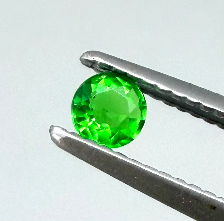0.22 ct natural grass-green diopside, round cut with intense color.