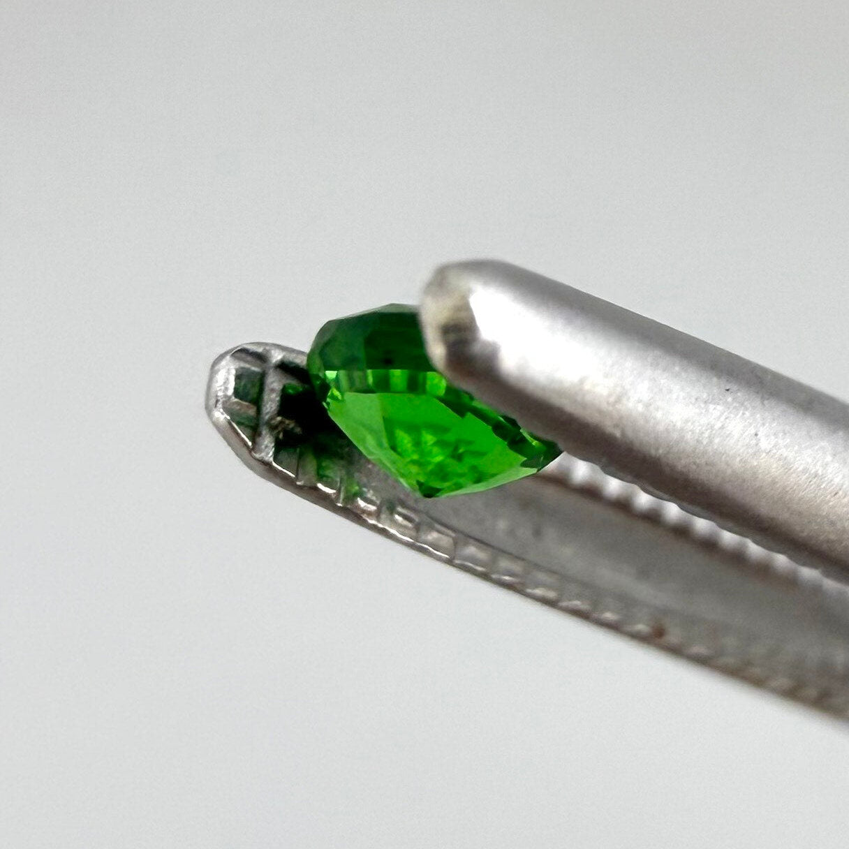 0.22 ct natural grass-green diopside, round cut with intense color.