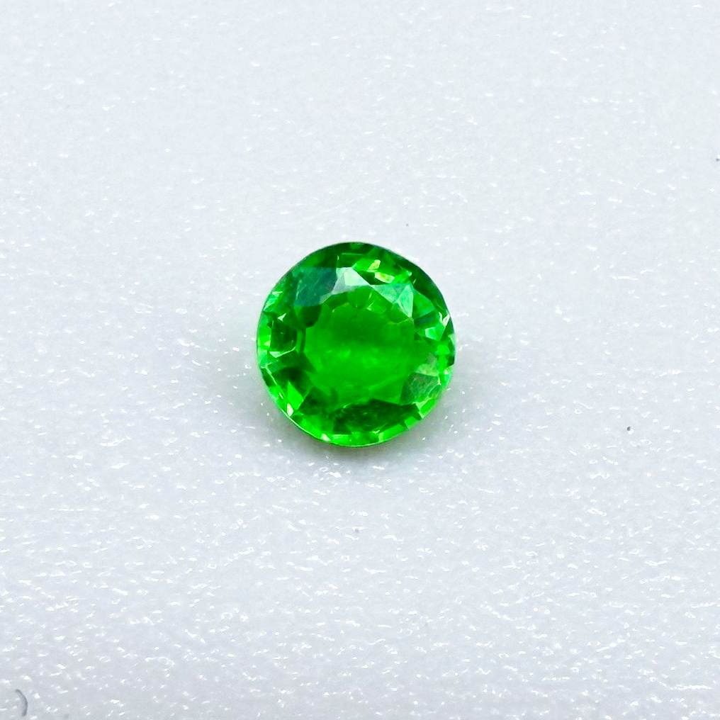 0.22 ct natural grass-green diopside, round cut with intense color.