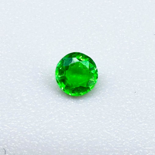 0.22 ct natural grass-green diopside, round cut with intense color.