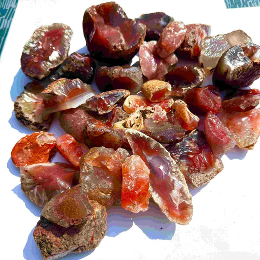 Shop Rough and uncut chalcedony carnelian lot in natural red-orange tones, untreated raw gemstones.