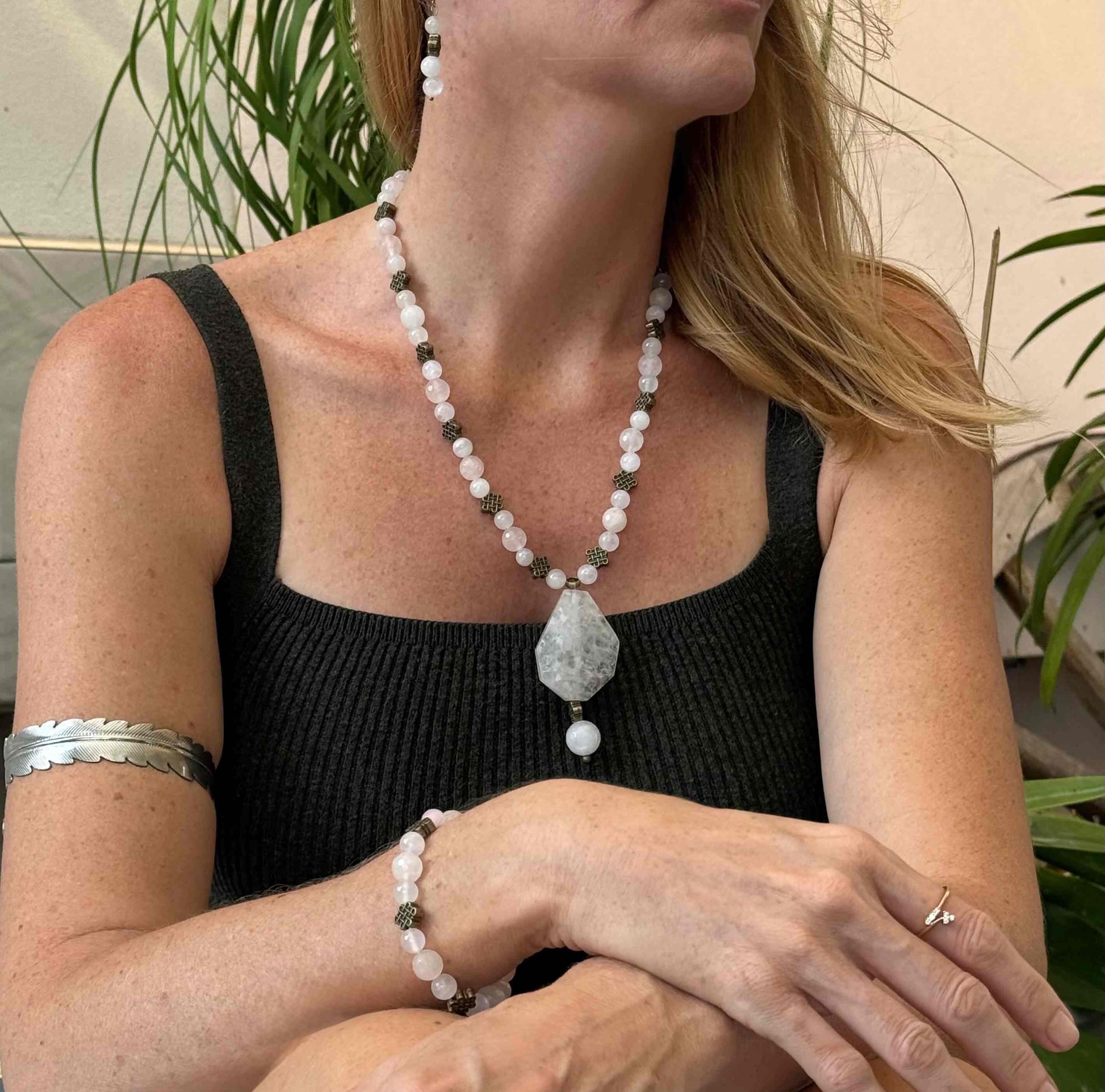 Rose quartz beaded jewelry set with golden spacers, including necklace with pendant, bracelet, and earrings in soft pink tones.