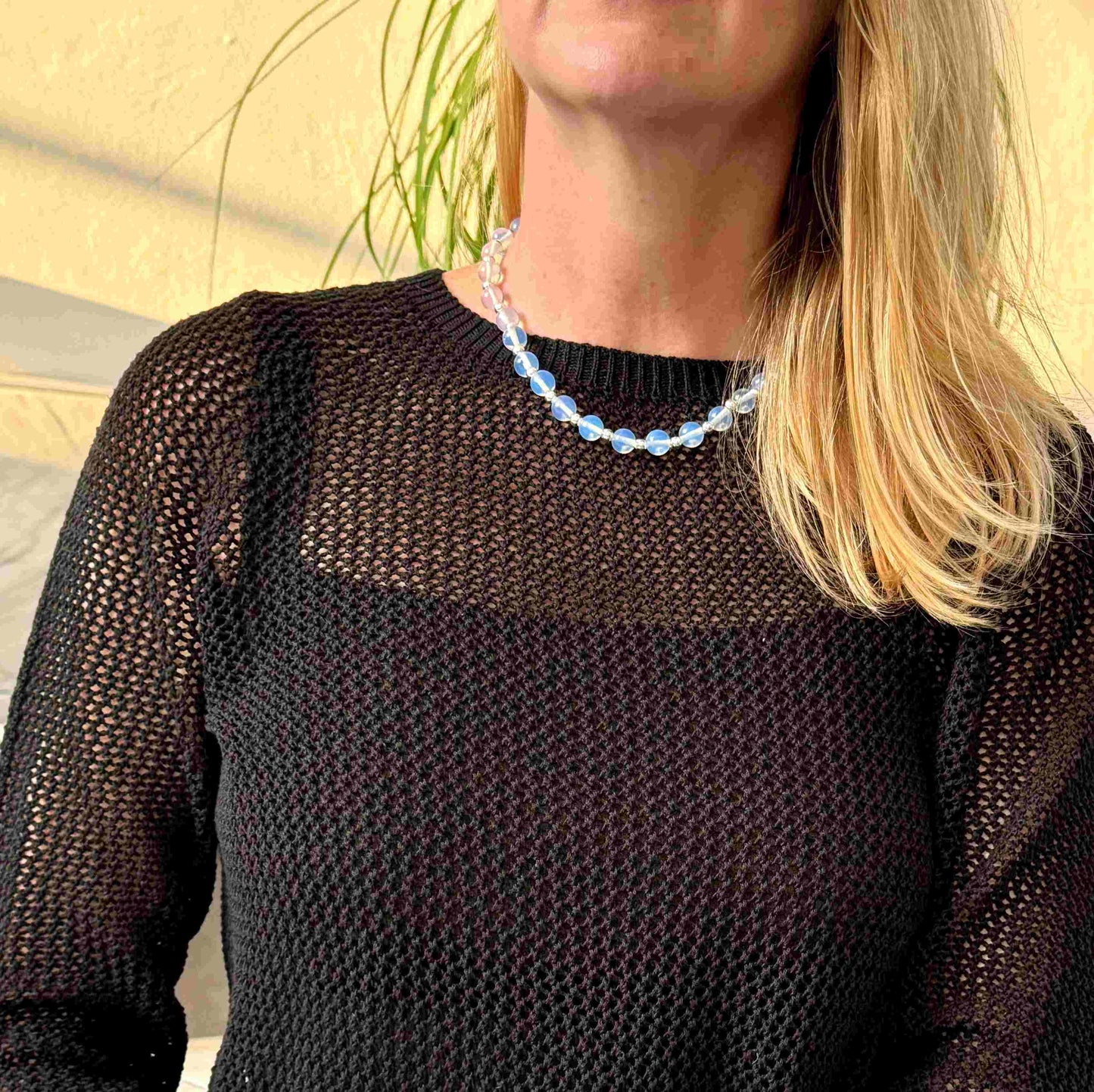 Necklace with light blue beads and silver accents on a gray background
