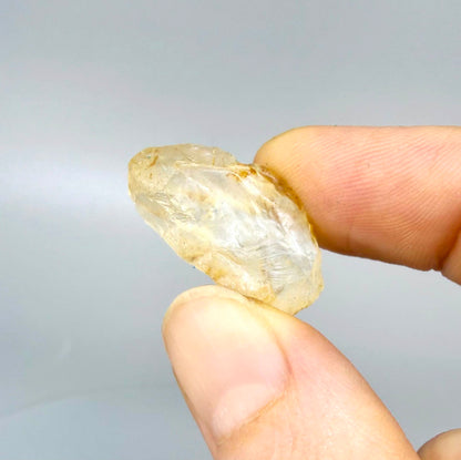 Natural champagne-gold topaz rough with warm golden tones, uncut and untreated, photographed on neutral background.