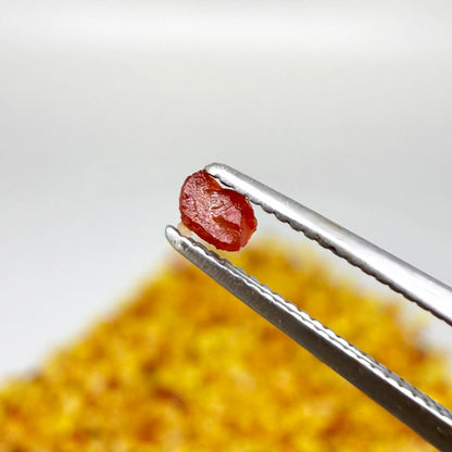 Natural sapphire rough with warm yellow-orange hues and subtle color variation, uncut corundum photographed on neutral background.