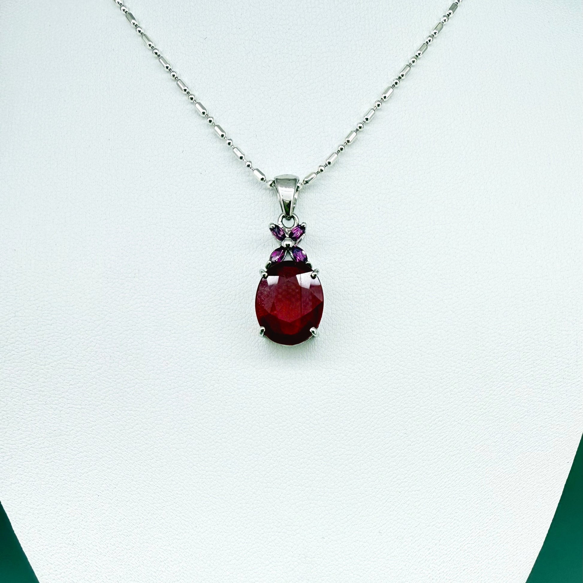 White gold plated silver pendant featuring a 7.87 ct ruby and 0.33 ct rhodolite garnets; elegant red and pink gemstone design.
