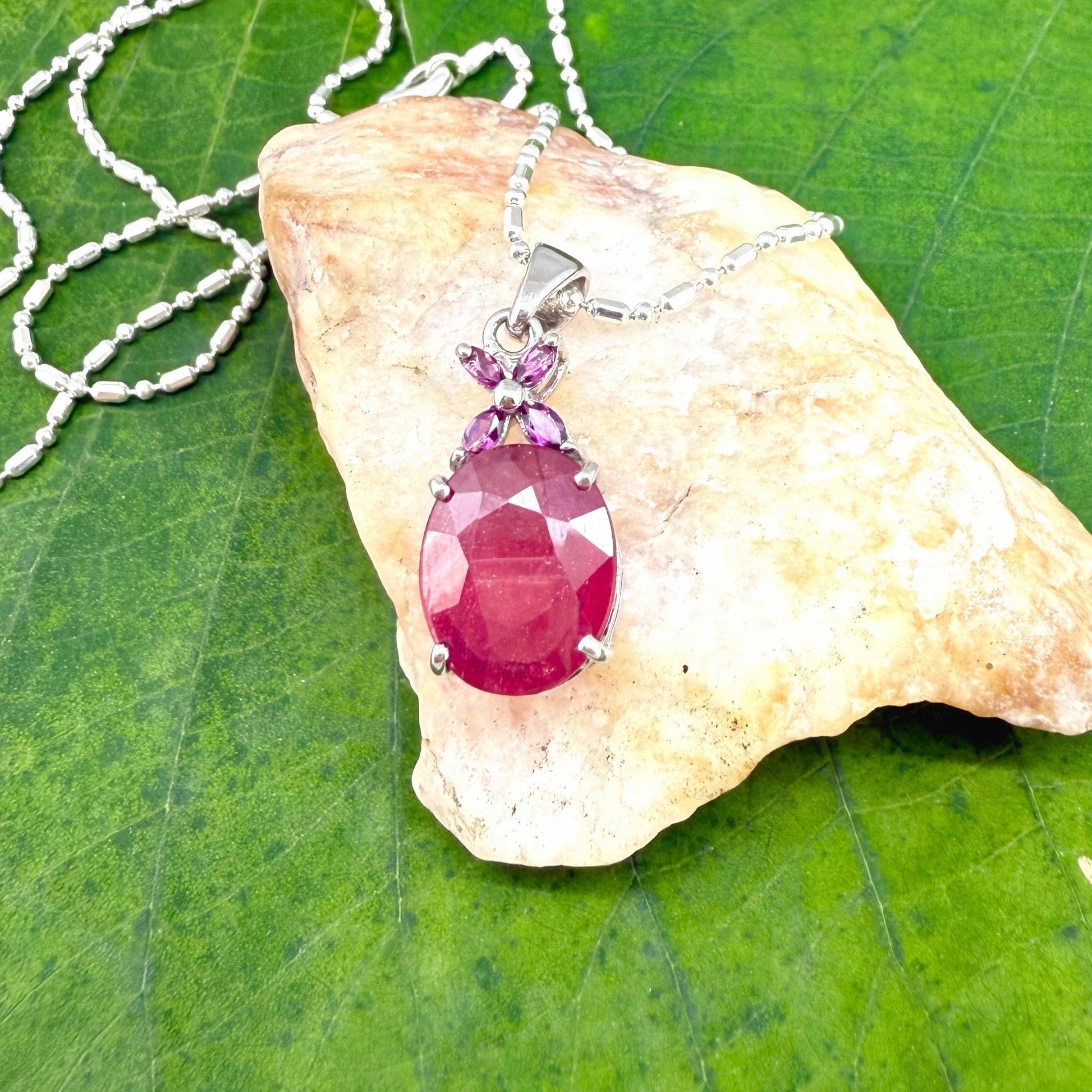 White gold plated silver pendant featuring a 7.87 ct ruby and 0.33 ct rhodolite garnets; elegant red and pink gemstone design.