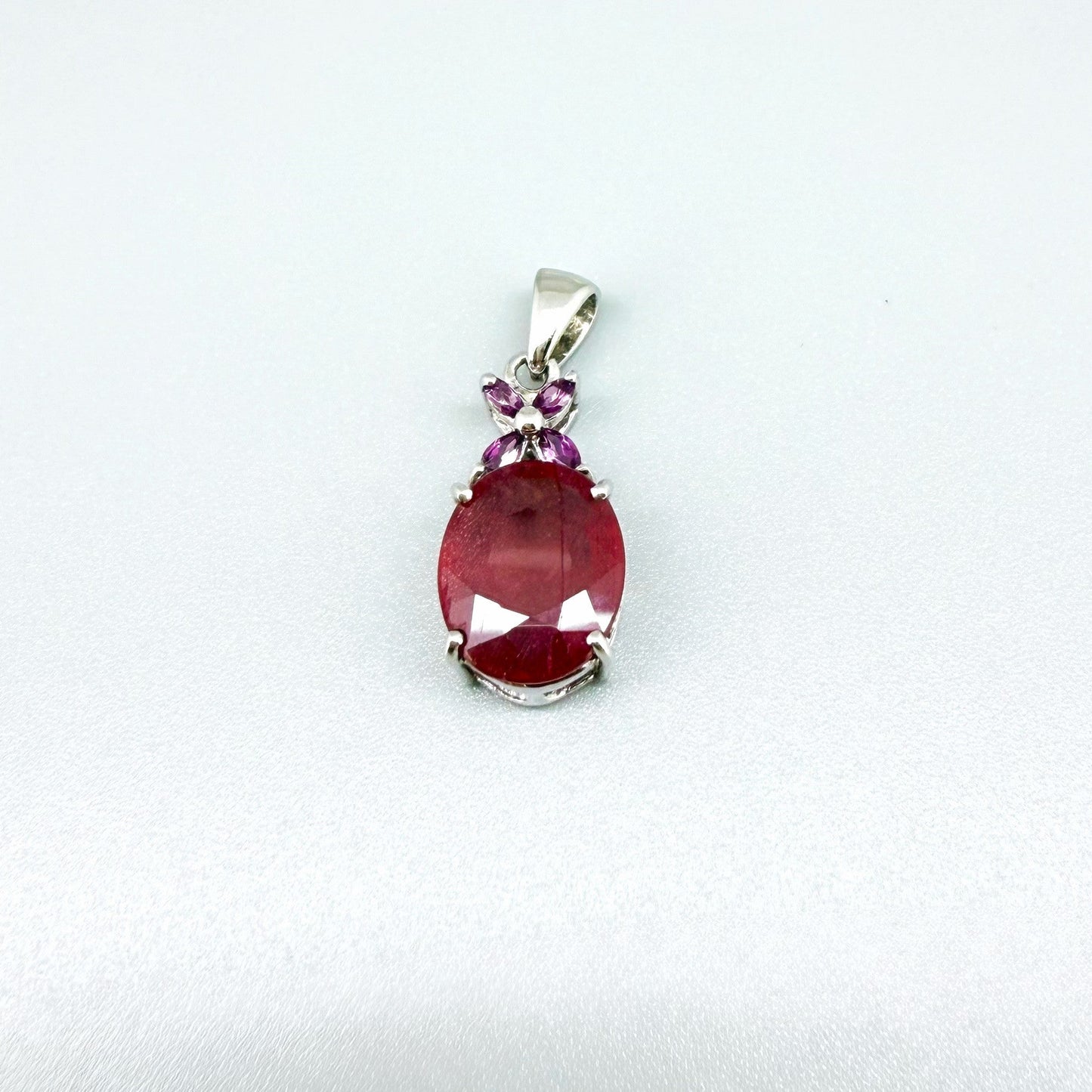White gold plated silver pendant featuring a 7.87 ct ruby and 0.33 ct rhodolite garnets; elegant red and pink gemstone design.