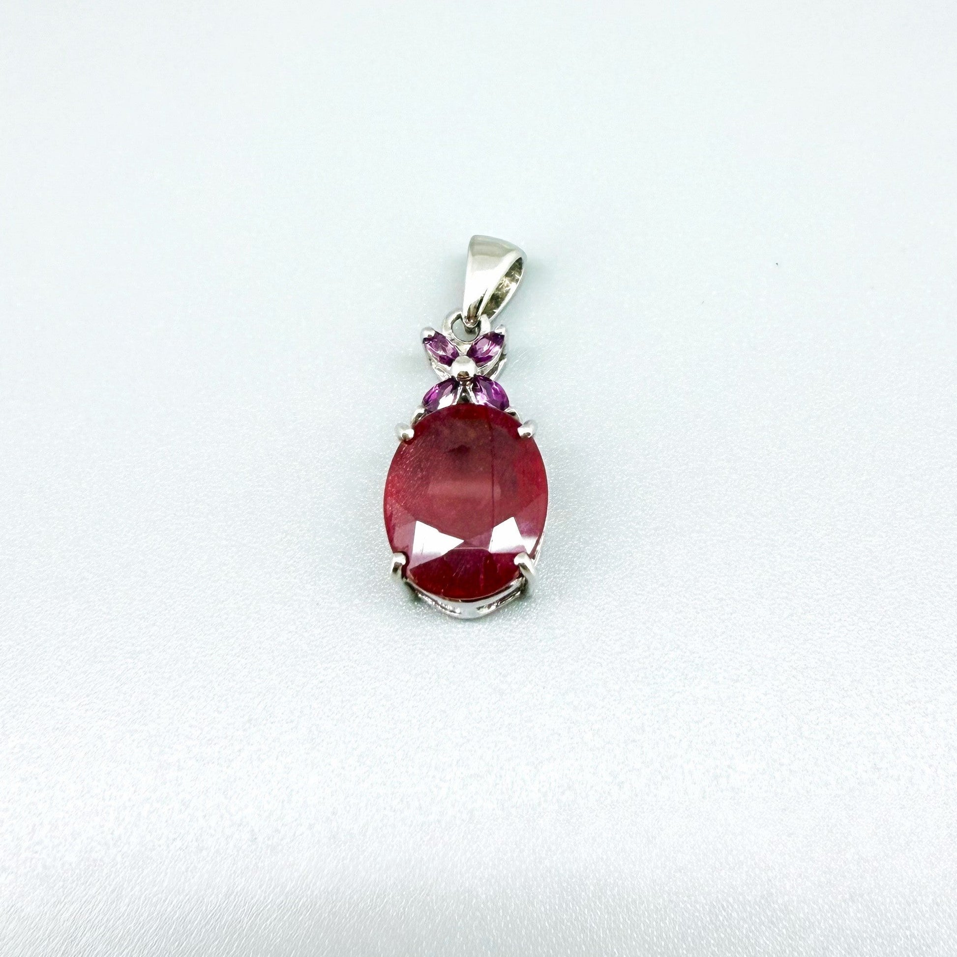 White gold plated silver pendant featuring a 7.87 ct ruby and 0.33 ct rhodolite garnets; elegant red and pink gemstone design.