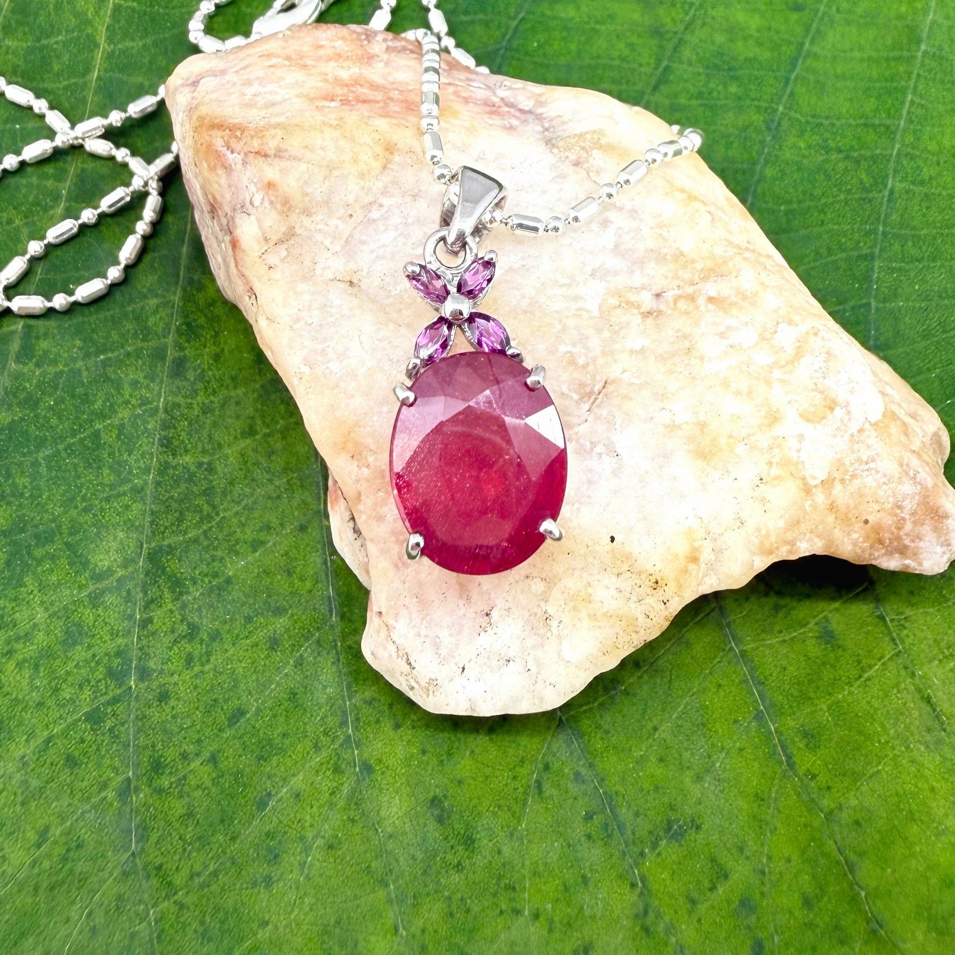White gold plated silver pendant featuring a 7.87 ct ruby and 0.33 ct rhodolite garnets; elegant red and pink gemstone design.