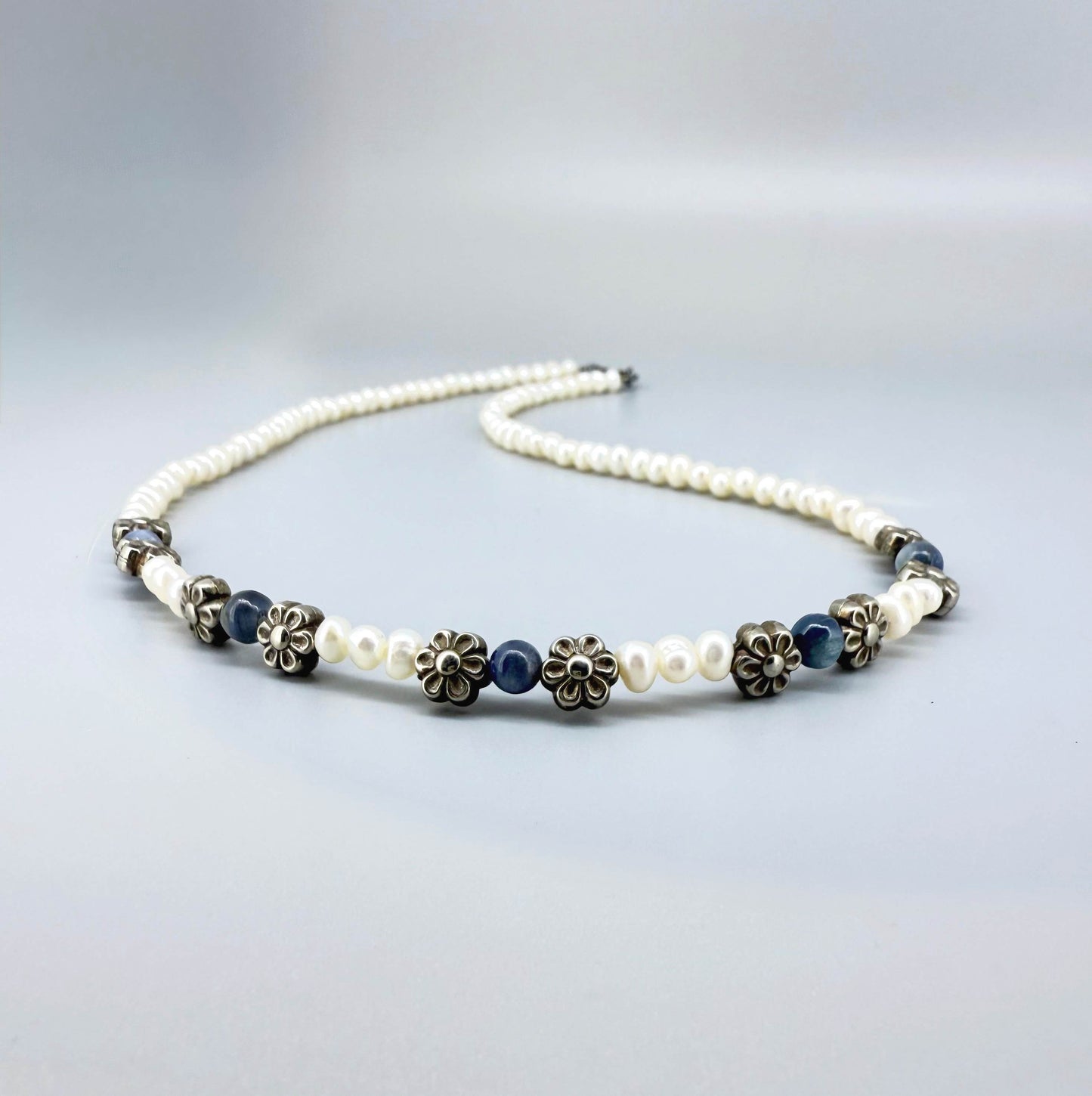 Japan pearl and sapphire necklace with floral metal spacer elements, 42 cm / 16.5 in long, featuring white pearls and deep blue stones.