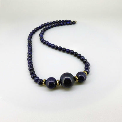 Necklace with dark blue goldstone beads on a white background