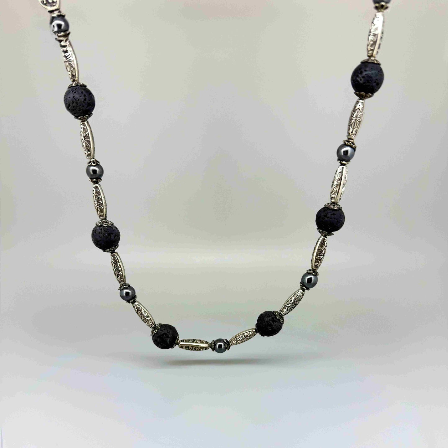 Handcrafted lava and hematite beaded necklace, 58 cm, in black and metallic tones.