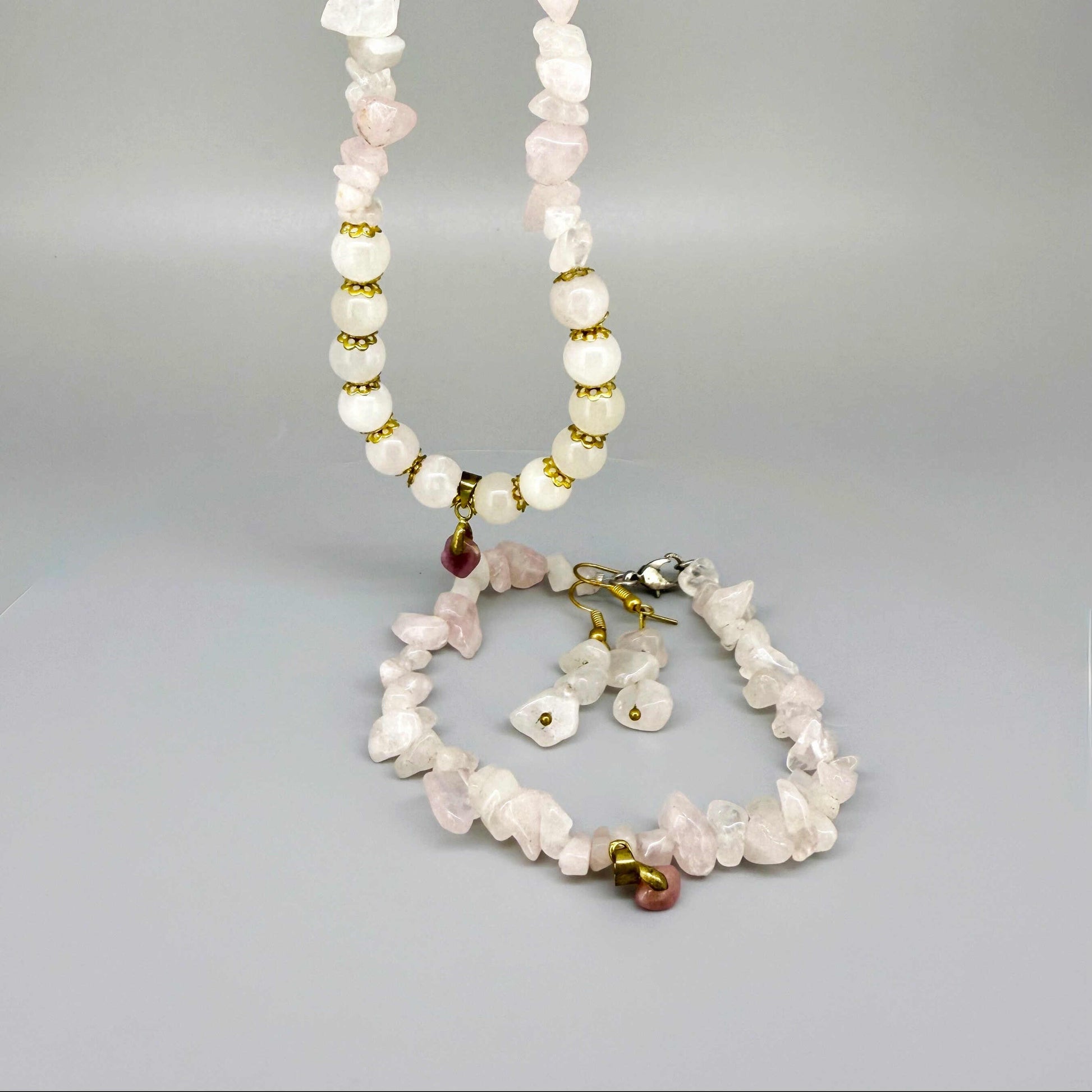 Rose quartz jewelry set with necklace, bracelet, and earrings in soft pink and gold tones, handcrafted with natural rose quartz beads.