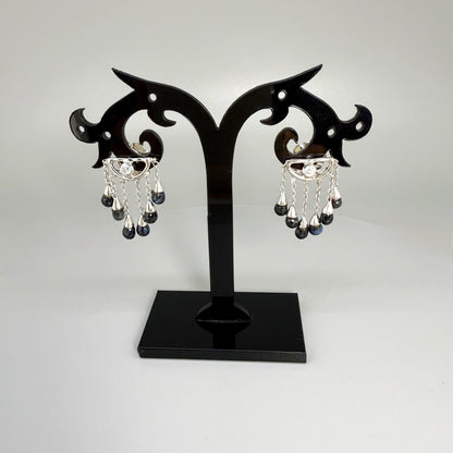 Necklace, bracelet and earrings set in white gold plated sterling silver with dark blue pineapple-cut sapphires, elegant jewelry displayed on neutral background.