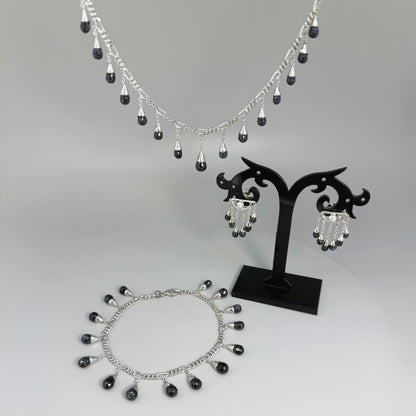 Necklace, bracelet and earrings set in white gold plated sterling silver with dark blue pineapple-cut sapphires, elegant jewelry displayed on neutral background.