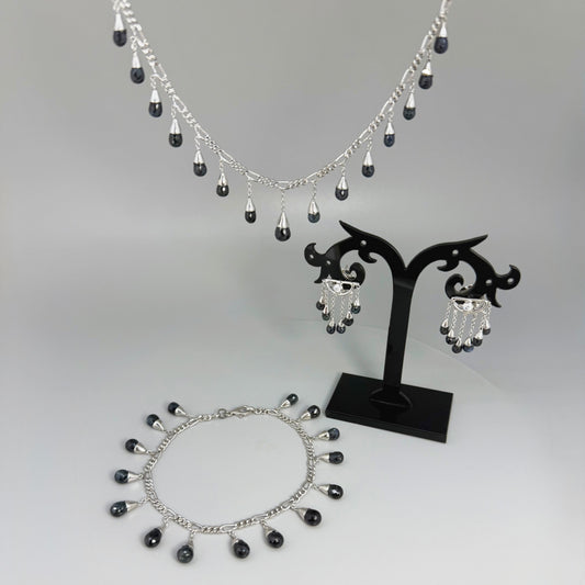 Necklace, bracelet and earrings set in white gold plated sterling silver with dark blue pineapple-cut sapphires, elegant jewelry displayed on neutral background.