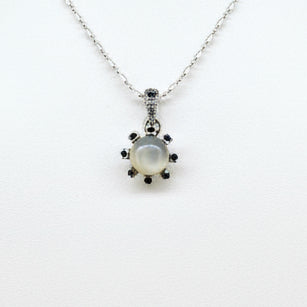 Handcrafted pendant featuring 3.75 ct natural moonstone and 0.35 ct blue sapphires set in white-gold-plated sterling silver.