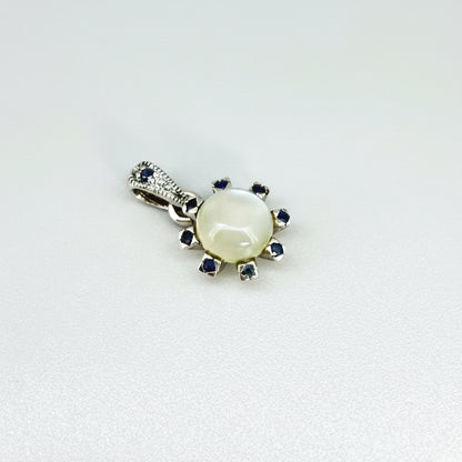 Handcrafted pendant featuring 3.75 ct natural moonstone and 0.35 ct blue sapphires set in white-gold-plated sterling silver.
