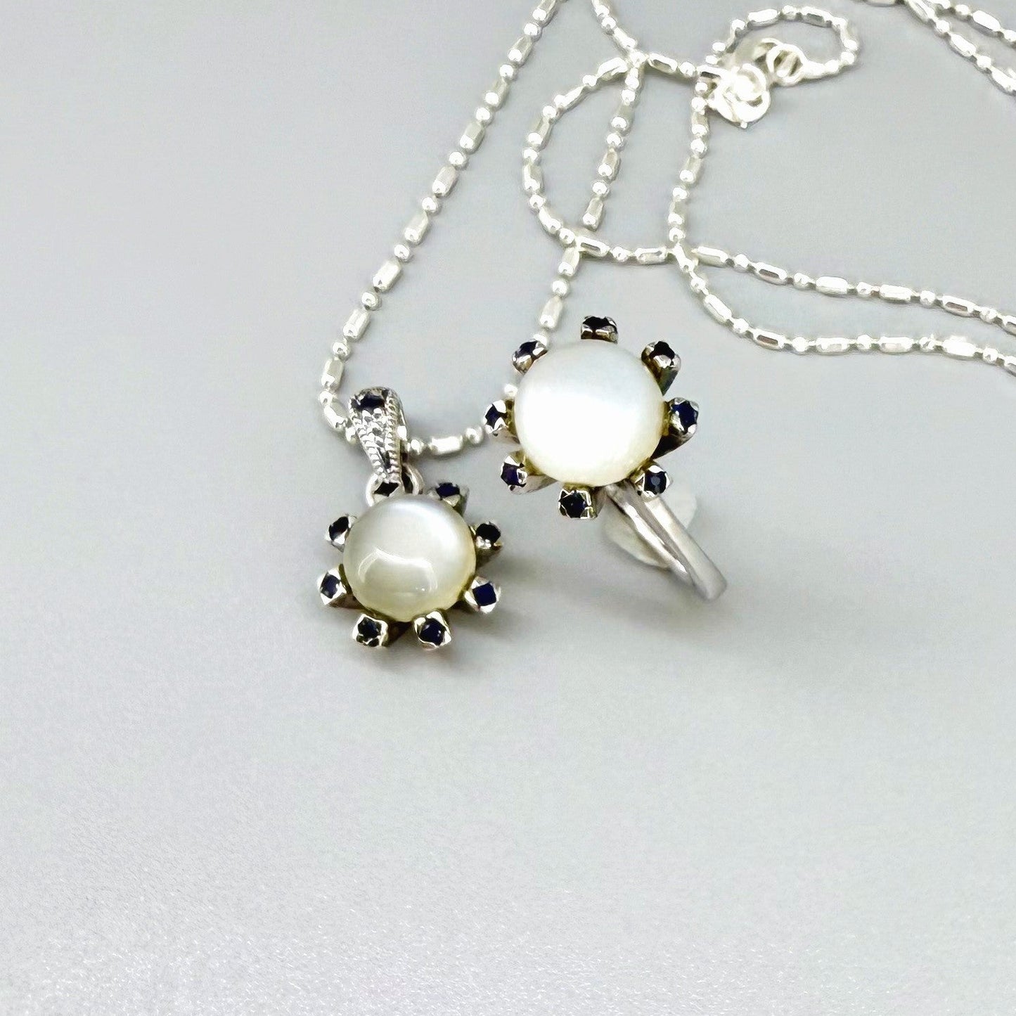 Handcrafted pendant featuring 3.75 ct natural moonstone and 0.35 ct blue sapphires set in white-gold-plated sterling silver.